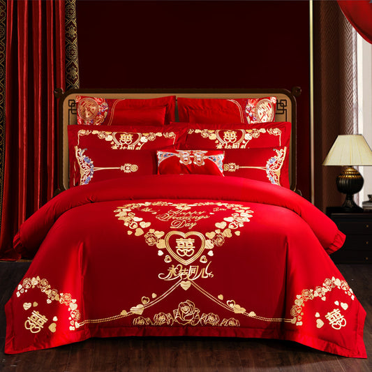 Red wedding-themed bedding set with intricate designs on a bed in a room.