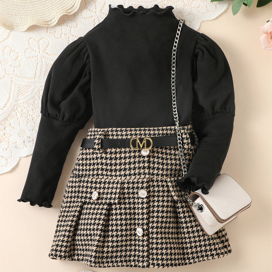 Black long-sleeve top with ruffled collar and houndstooth skirt on a neutral background