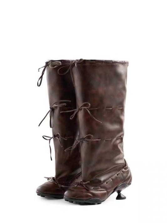 Pair of brown leather knee-high boots with laces on a white background