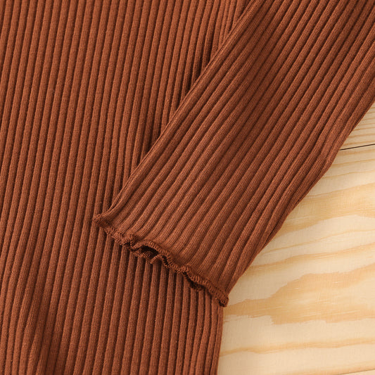 Brown ribbed sweater sleeve on a wooden surface