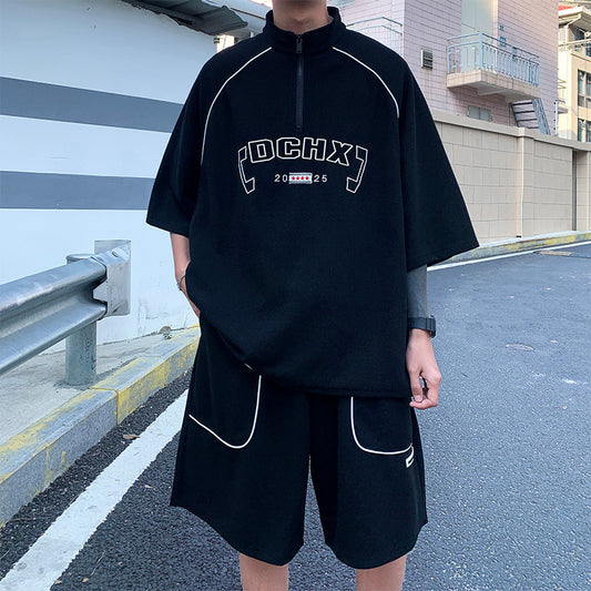 Person wearing a black outfit with white text and logos on a street.