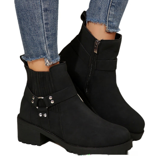 Black ankle boots with silver buckles worn with blue jeans on a white background
