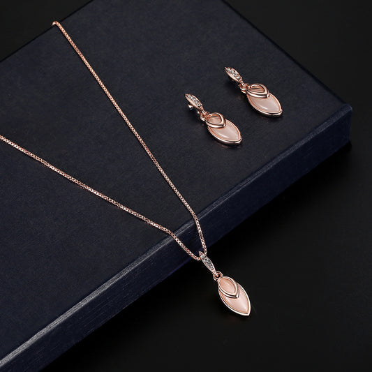 Rose gold necklace and earrings on a dark surface