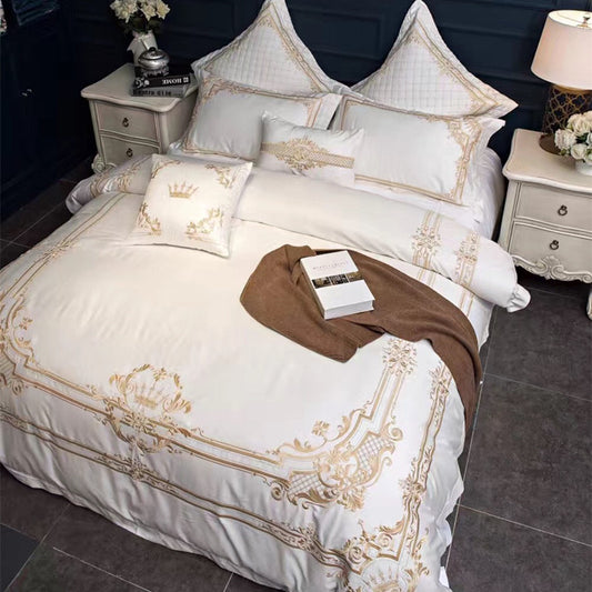 Luxurious bed with white and gold bedding in a bedroom setting.