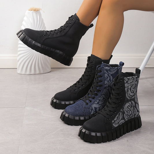 Black and blue boots with floral pattern on a light gray floor.