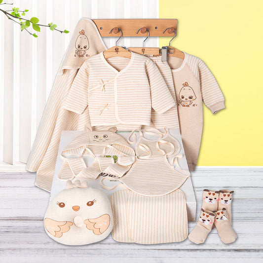 Collection of baby clothes and accessories on a wooden surface with a yellow wall background.