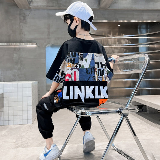 Person wearing a black t-shirt with colorful graphics and 'LINKLK' branding, sitting on a transparent chair.