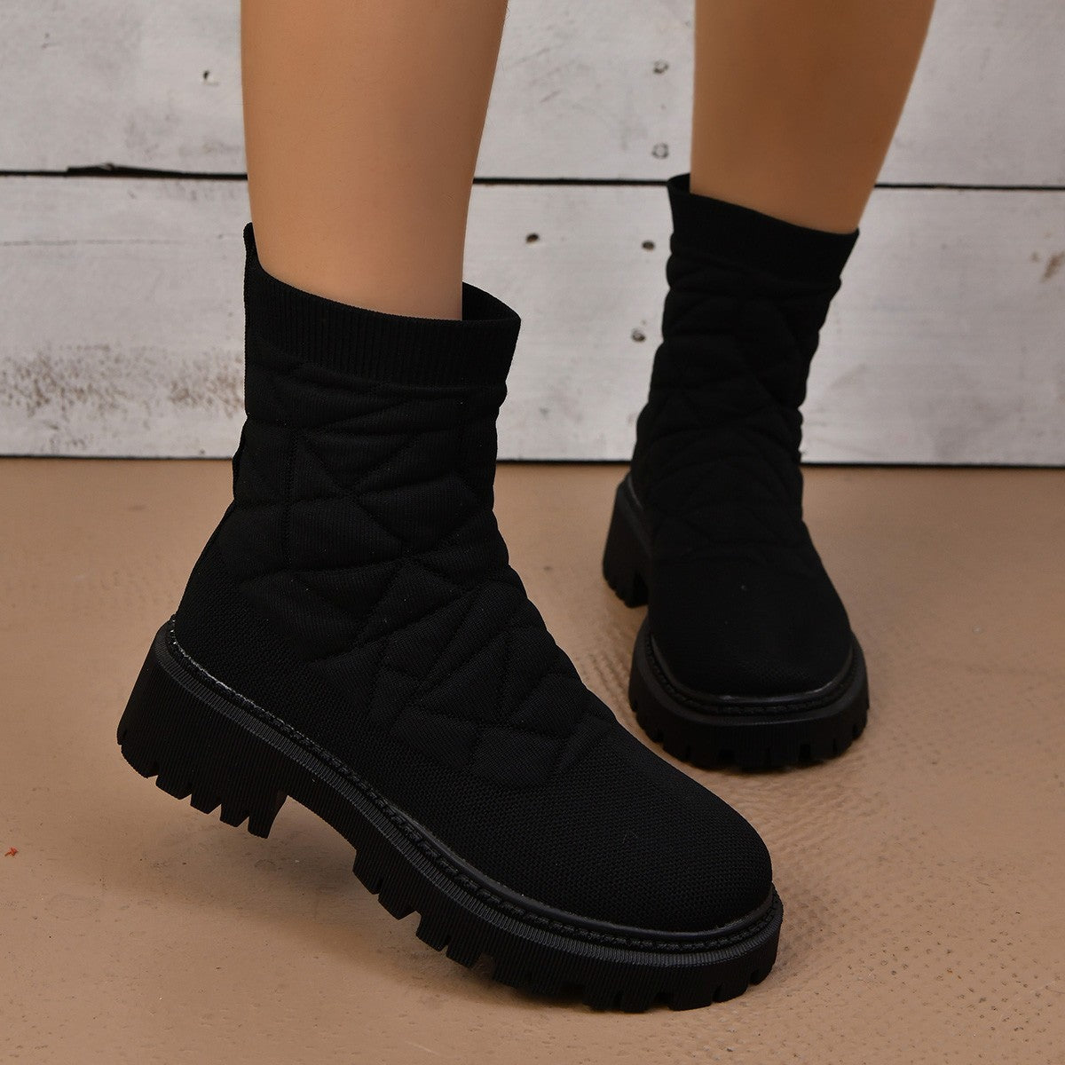 Black winter boots worn with a neutral background