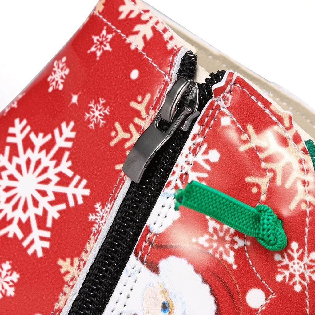 Close-up of a red fabric with white snowflakes and a black zipper, featuring a green bow and Santa Claus design.