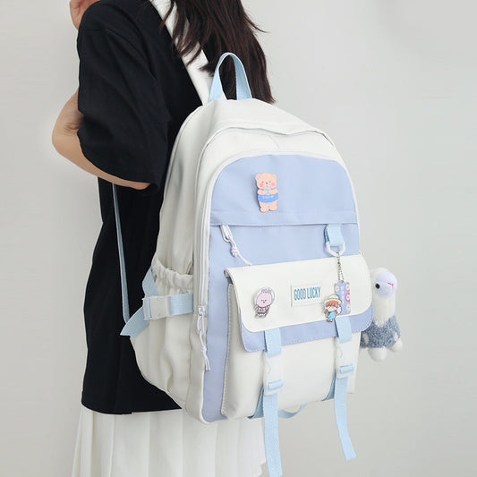 Person wearing a white and light blue backpack with cartoon character designs on a plain background