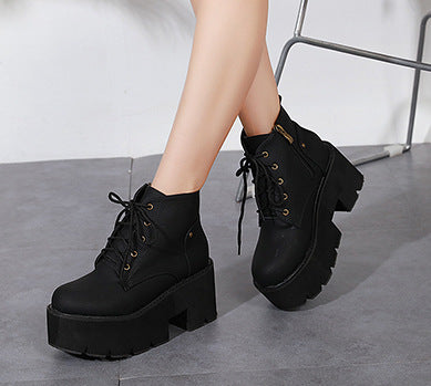 Black platform boots worn by a person on a gray floor.