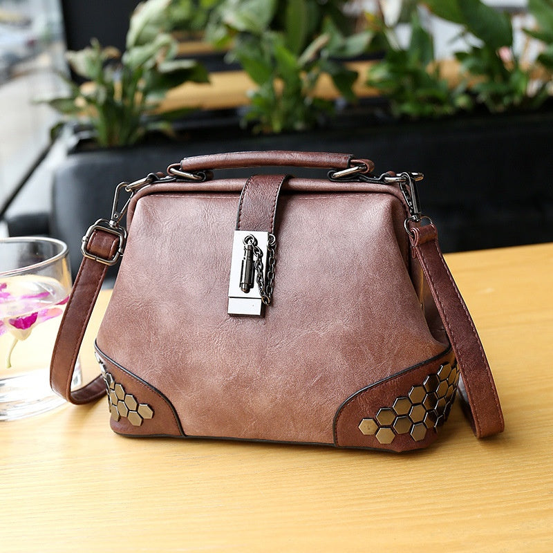 Brown handbag with decorative elements on a wooden surface