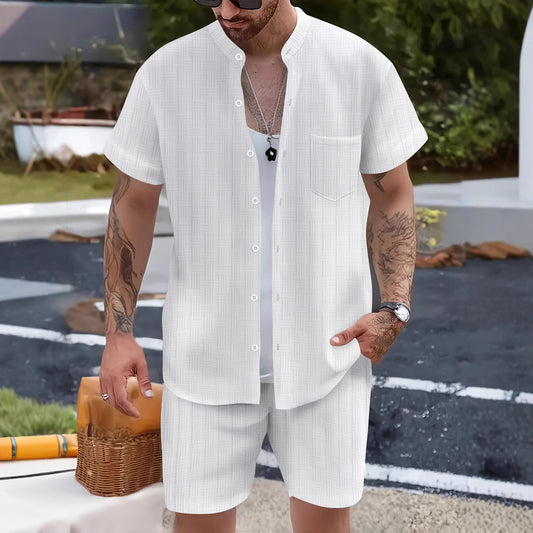 Man wearing a white striped shirt and shorts standing outdoors.