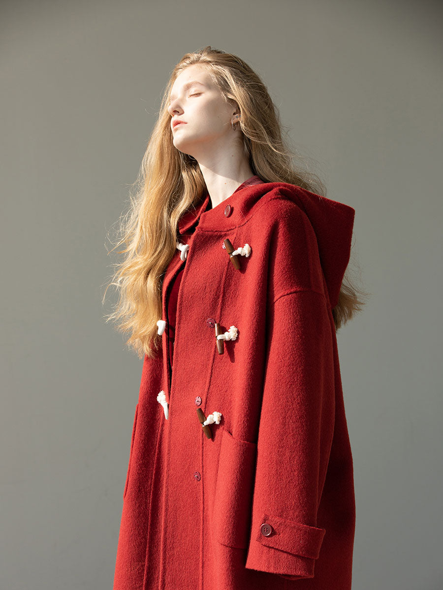 Person wearing a red coat with a hood against a neutral background