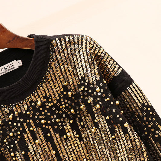 Black sweater with gold sequin details on a hanger
