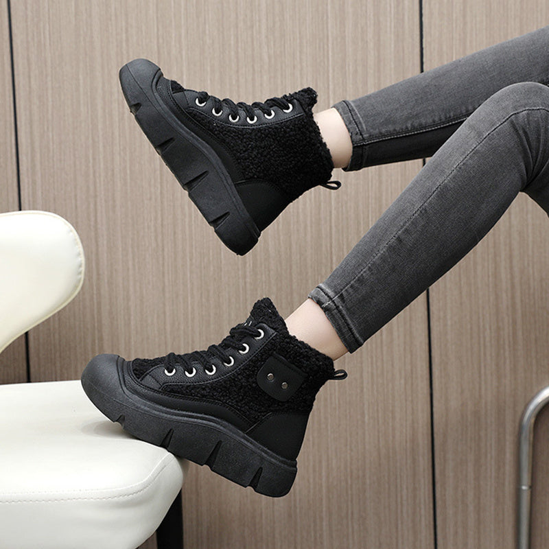 Black high-top sneakers with fuzzy texture worn by a person sitting on a white chair.