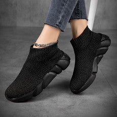 Black slip-on shoes worn with jeans on a gray background
