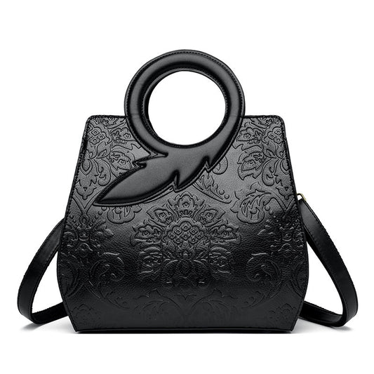 Black embossed handbag with unique handle design on a white background