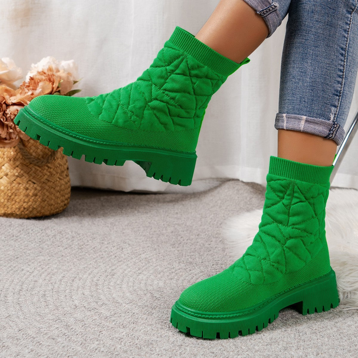 Green quilted ankle boots worn with jeans on a neutral background