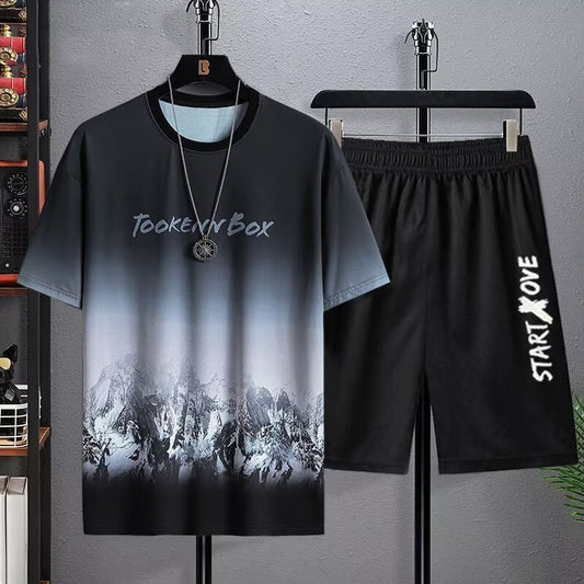 Black t-shirt with mountain design and black shorts with 'Start Love' text on a gray background.