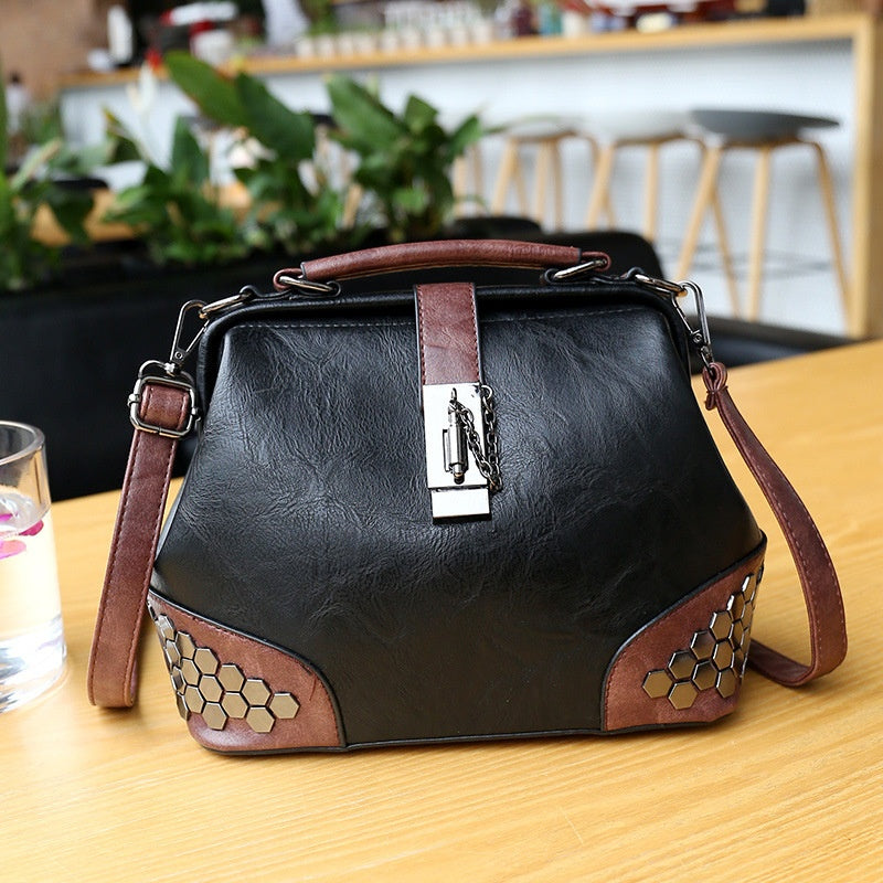 Black leather handbag with brown accents on a wooden table