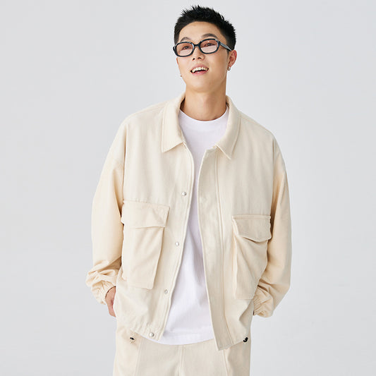 Man wearing a beige jacket over a white shirt on a plain background