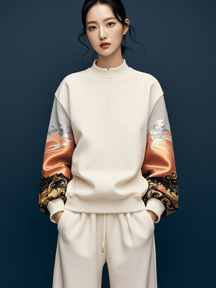 Person wearing a cream-colored outfit with patterned sleeves against a dark background