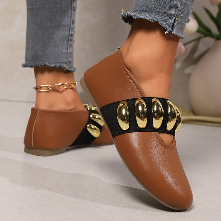 Brown loafers with gold accents worn by a person in jeans.