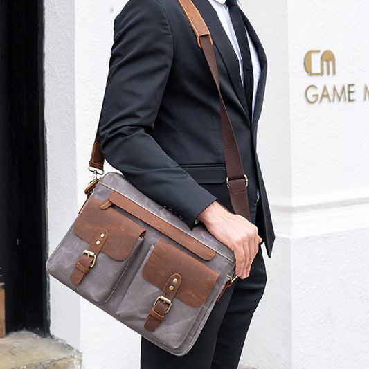 Person holding a gray and brown leather bag against a white wall with 'GAME' branding.