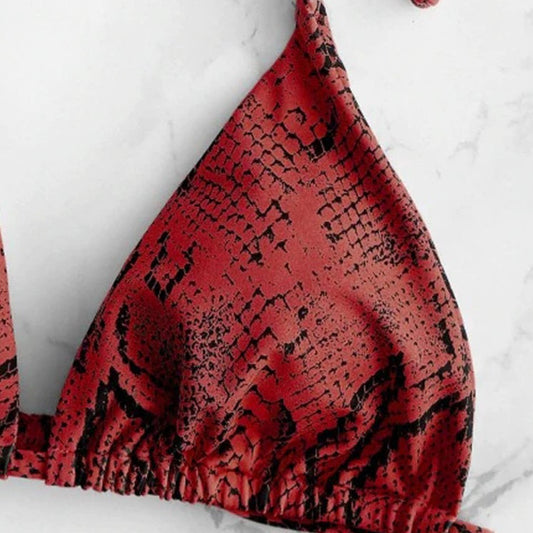 Red bikini top with black abstract pattern on a white marble background