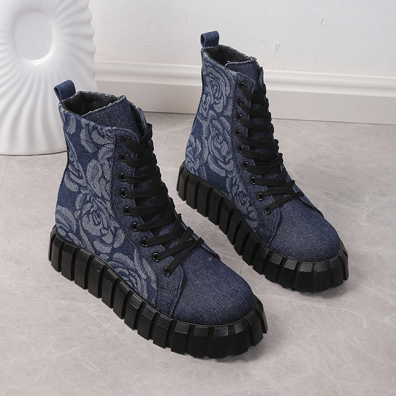 Blue floral-patterned boots with black soles on a light gray surface.