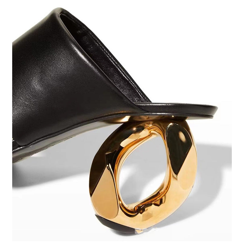 Black sandal with a gold metallic heel on a white background