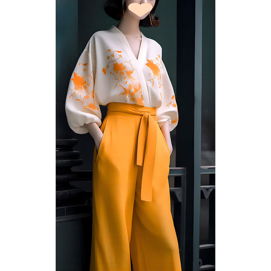 Mannequin wearing a white top with orange floral patterns and yellow pants against a dark background