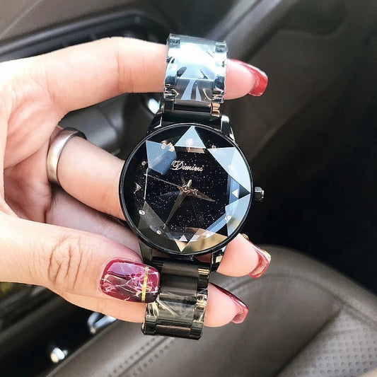 Hand holding a diamond-studded watch with a black face and silver band.