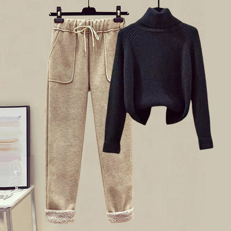 Black sweater and beige pants on a hanger against a neutral background