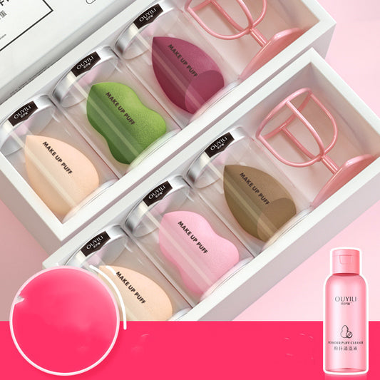 Set of makeup sponges and applicators in a box with OUVII branding, featuring a pink bottle on a pink background.