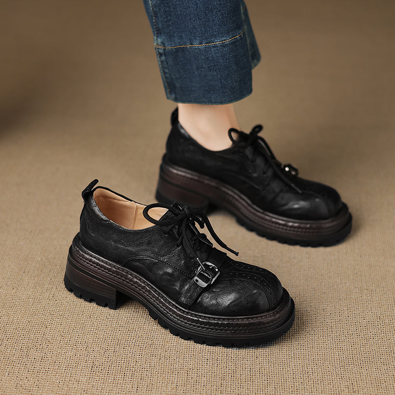 Black leather shoes with a buckle on a beige surface