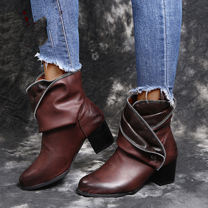 Brown leather boots worn with ripped jeans on a textured gray background