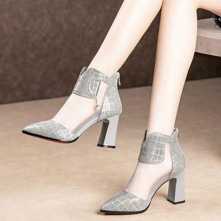 Silver high-heeled shoes worn by a person on a neutral background