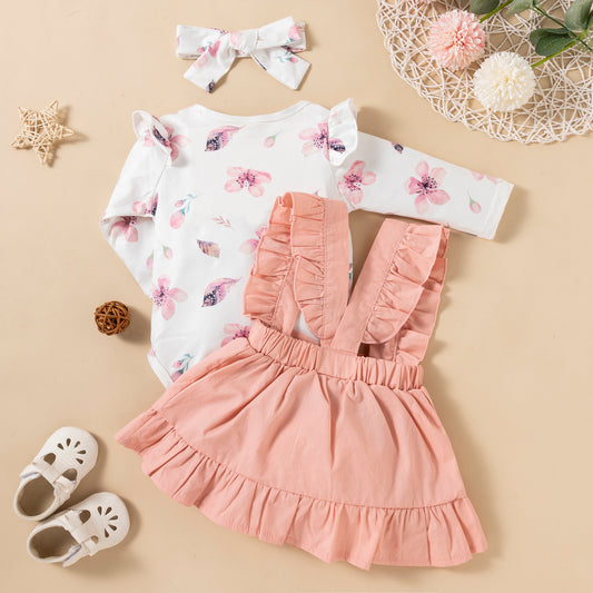 Baby outfit with floral top and pink ruffled skirt on a beige background