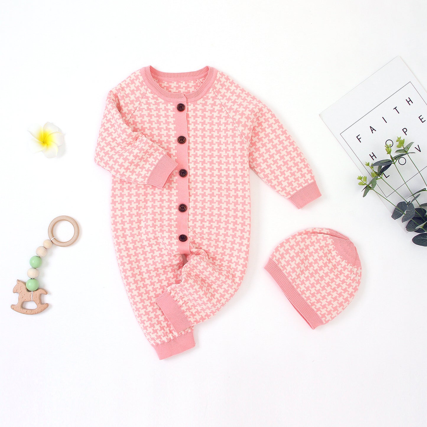 Pink baby outfit with matching hat and toy on a white background