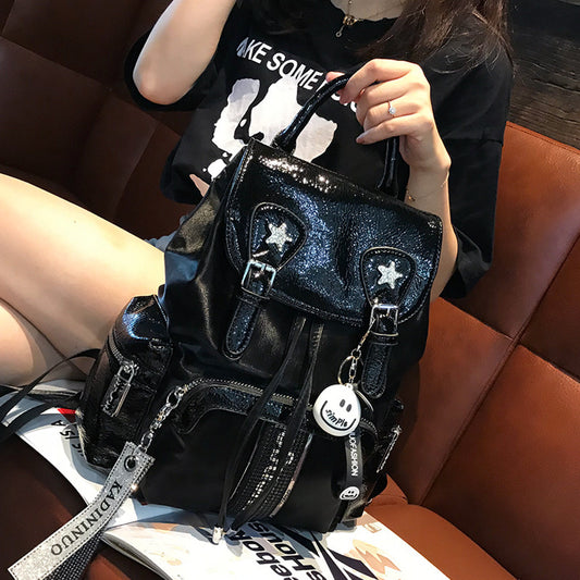 Person holding a black glittery handbag with star accents on a brown leather couch.