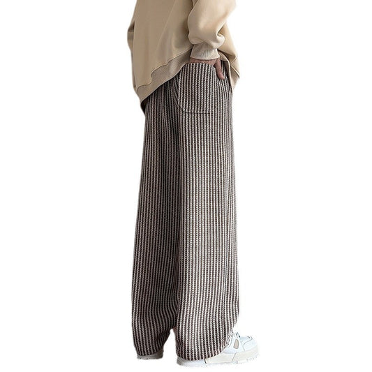 Person wearing a beige sweater and plaid pants on a white background