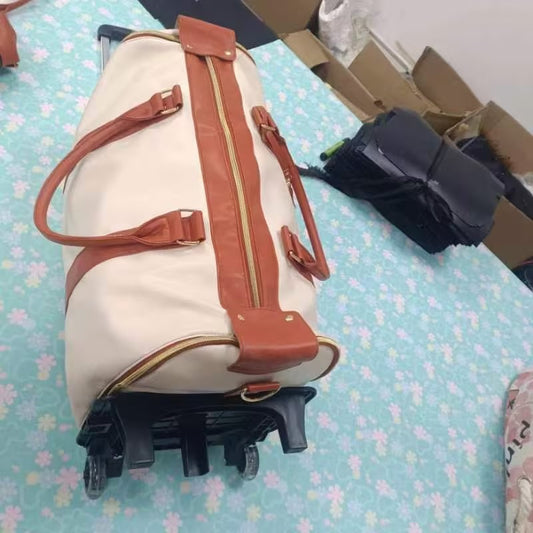 Beige duffel bag with brown straps on a floral-patterned surface