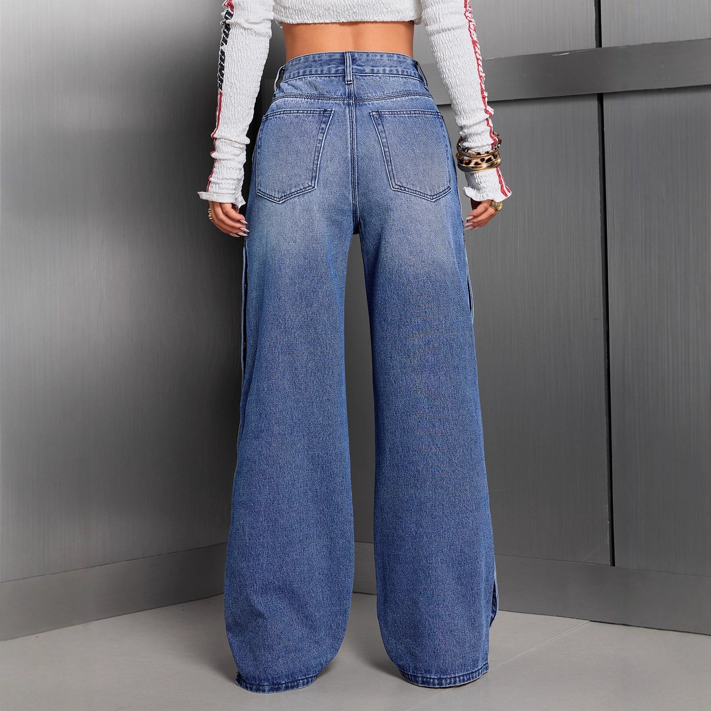 Person wearing blue wide-leg jeans against a gray background