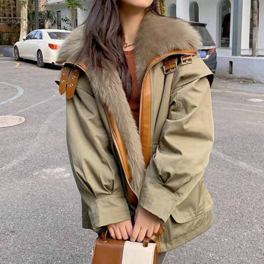 Person wearing a green parka with fur trim on a street.