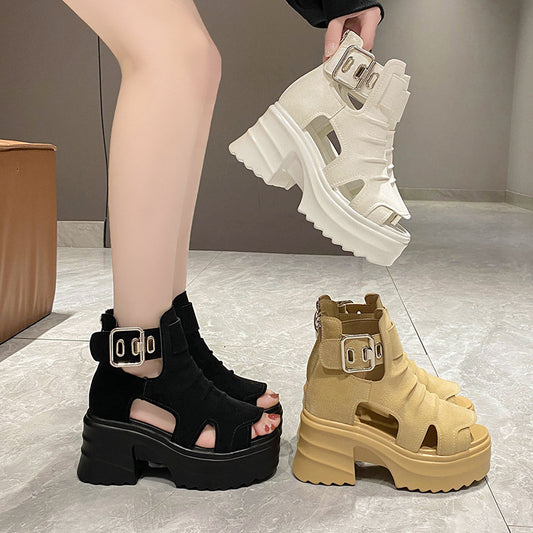 Black and beige platform sandals with buckles on a tiled floor.