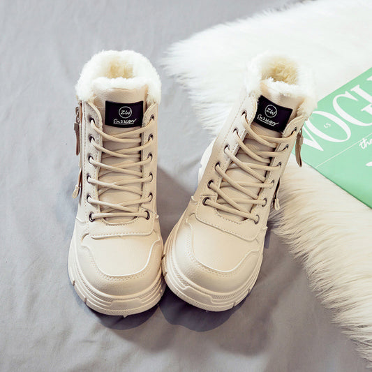 Pair of beige winter boots with fur lining on a light gray surface.