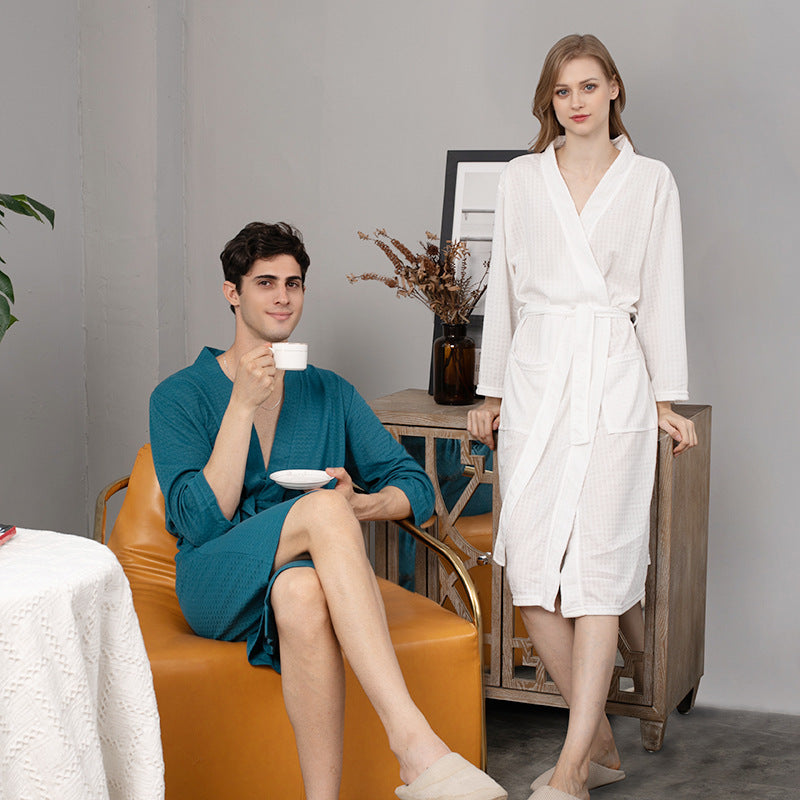 Man in teal robe holding a cup and saucer, woman in white robe standing in a room.