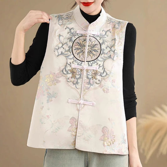 Person wearing a light-colored embroidered vest with floral patterns on a beige background